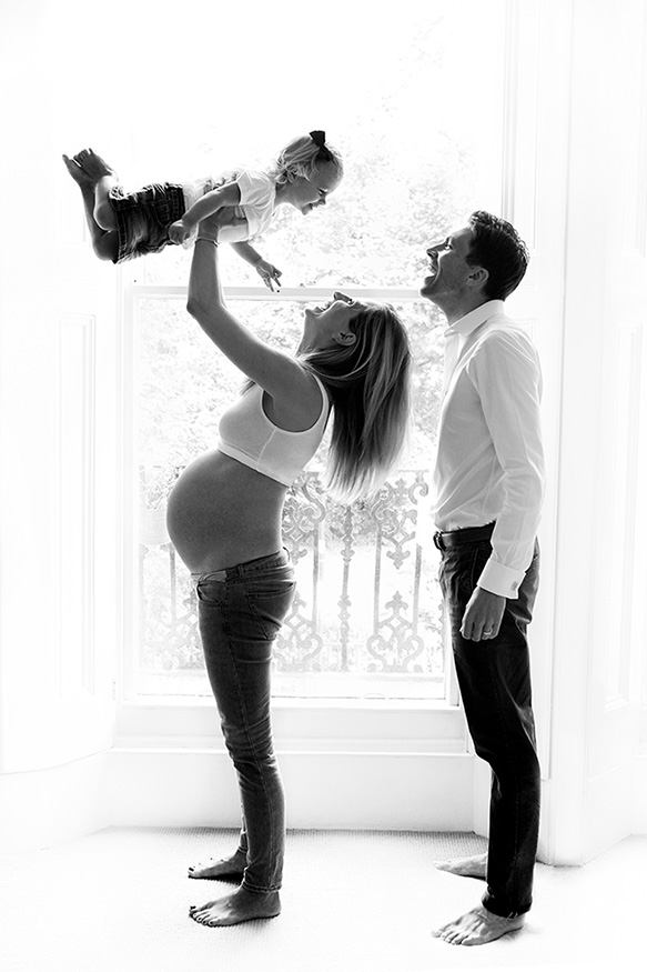 a couple with pregnant mum playing with their toddler during a maternity photography London